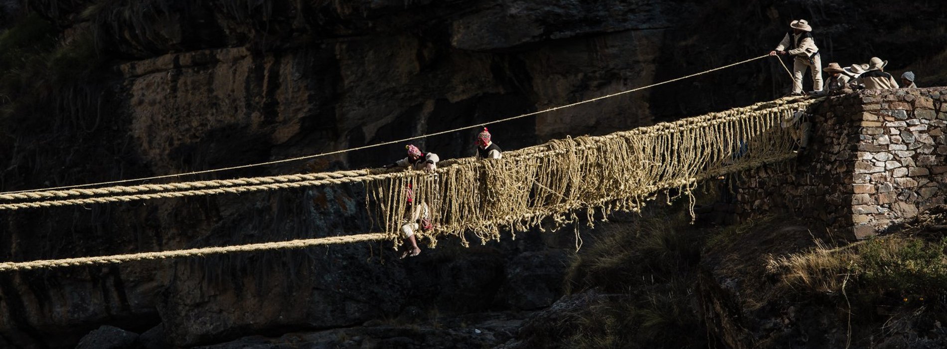 Smiling travelers on the Qeswachaka rope bridge with local guide